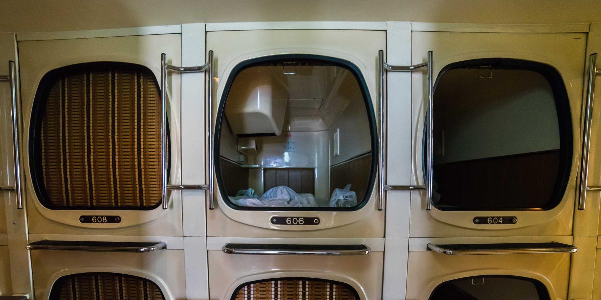 Mehrere klassische Kapselhotel-Schlafkabinen übereinander gestapelt, mit Schlafbereich und Bettzeug sichtbar