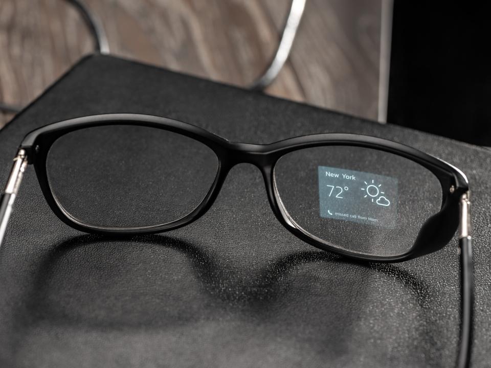 Smarte Brille mit eingeblendeter Wetteranzeige für New York auf dem Glas, stilvoll auf schwarzem Tisch platziert.____