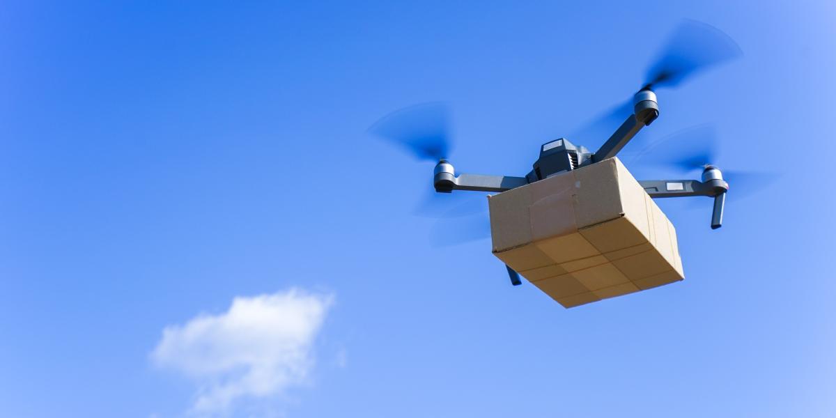 Drohne transportiert ein Paket am Himmel mit blauem Hintergrund und leichter Bewölkung
