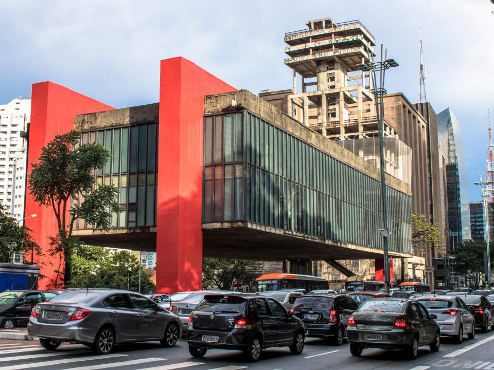 Moderne Architektur mit rotem Akzent und Glasfassade, São Paulo, vor starkem Straßenverkehr.____