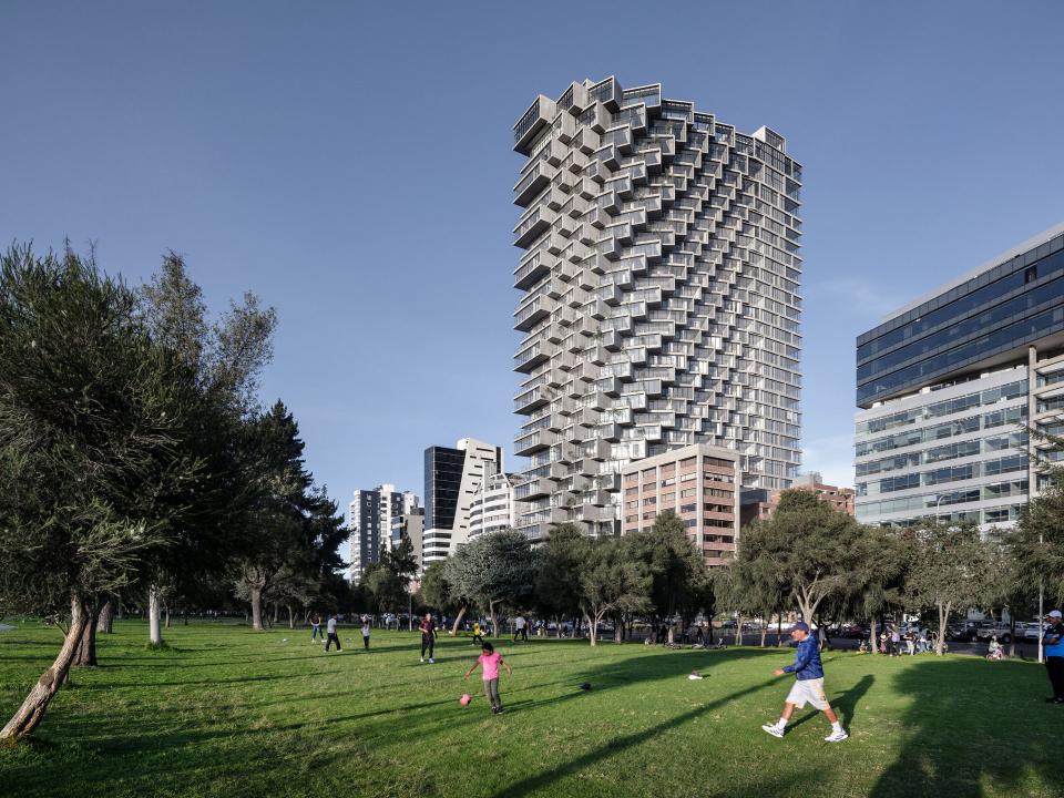 Hochhaus mit versetzten Balkonen neben einem Park mit spielenden Kindern.____