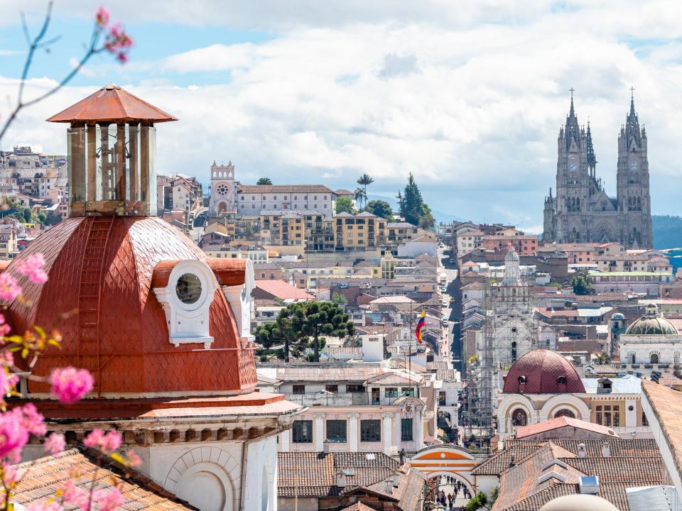 Die Stadt Quito mit roten Dächern und gotischer Kirche im Hintergrund.____