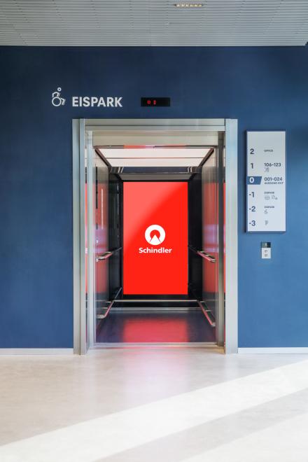 Moderner Schindler Aufzug im Eispark mit rotem Display und barrierefreier Zugangskennzeichnung.