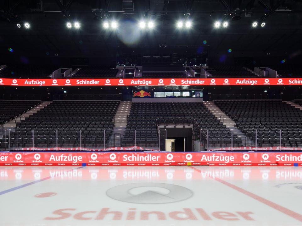 Innenansicht der Eishalle mit Werbung für Schindler Aufzüge an den LED-Banden und auf dem Eis.____