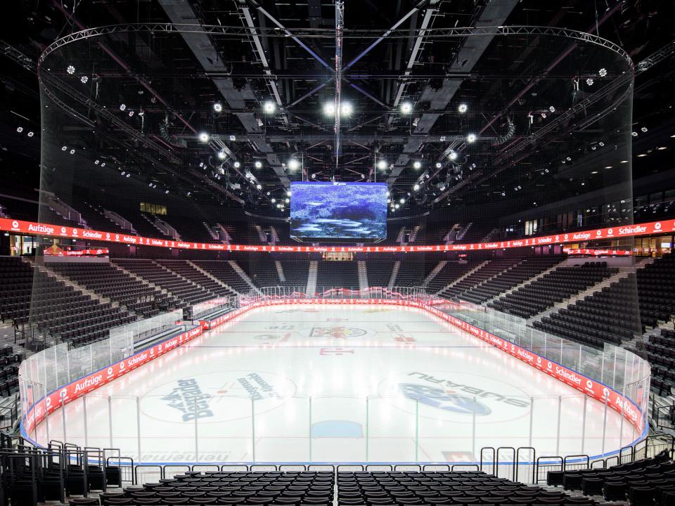 Große Eisfläche in moderner Arena mit umlaufender LED-Werbung für Schindler Aufzüge.____