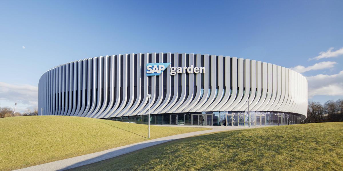 Außenansicht der SAP Garden Arena mit modernem Fassadendesign unter blauem Himmel.