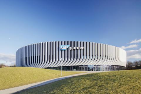 Außenansicht der SAP Garden Arena mit modernem Fassadendesign unter blauem Himmel.