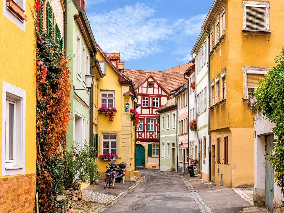 Bunte Fachwerkhäuser und enge, malerische Gasse in einer Altstadt.____
