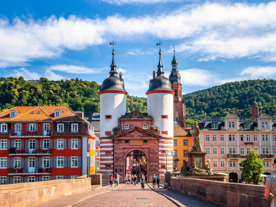 Heidelberger Brückentor und Altstadt mit bunten Häusern und Hügeln im Hintergrund.____