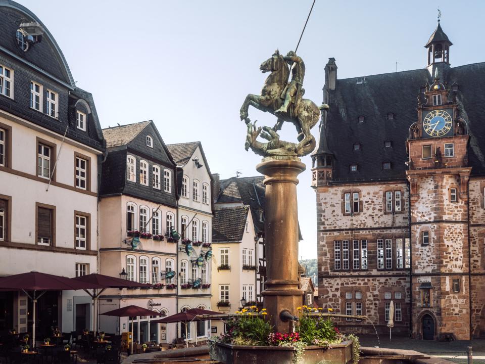 Historischer Marktplatz mit Statue und alten Gebäuden im Hintergrund.____