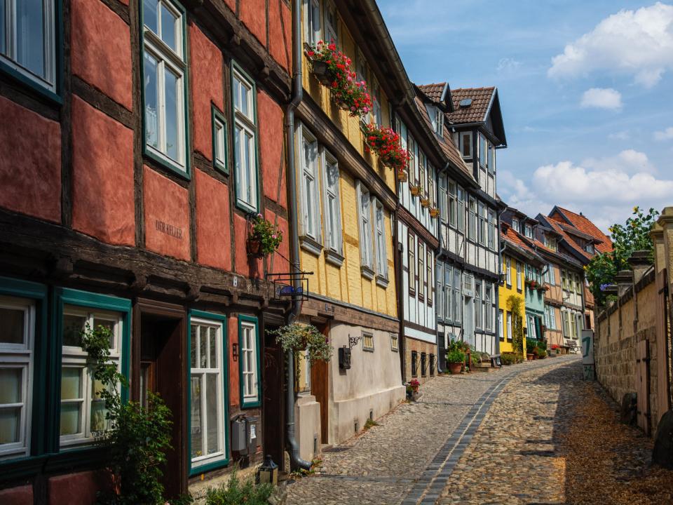 Bunte Fachwerkhäuser in einer kurvigen Straße mit Kopfsteinpflaster.____