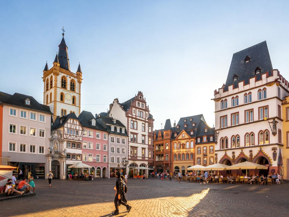 Hauptmarkt in Trier mit farbenfrohen Gebäuden und Menschen im Sonnenlicht.____