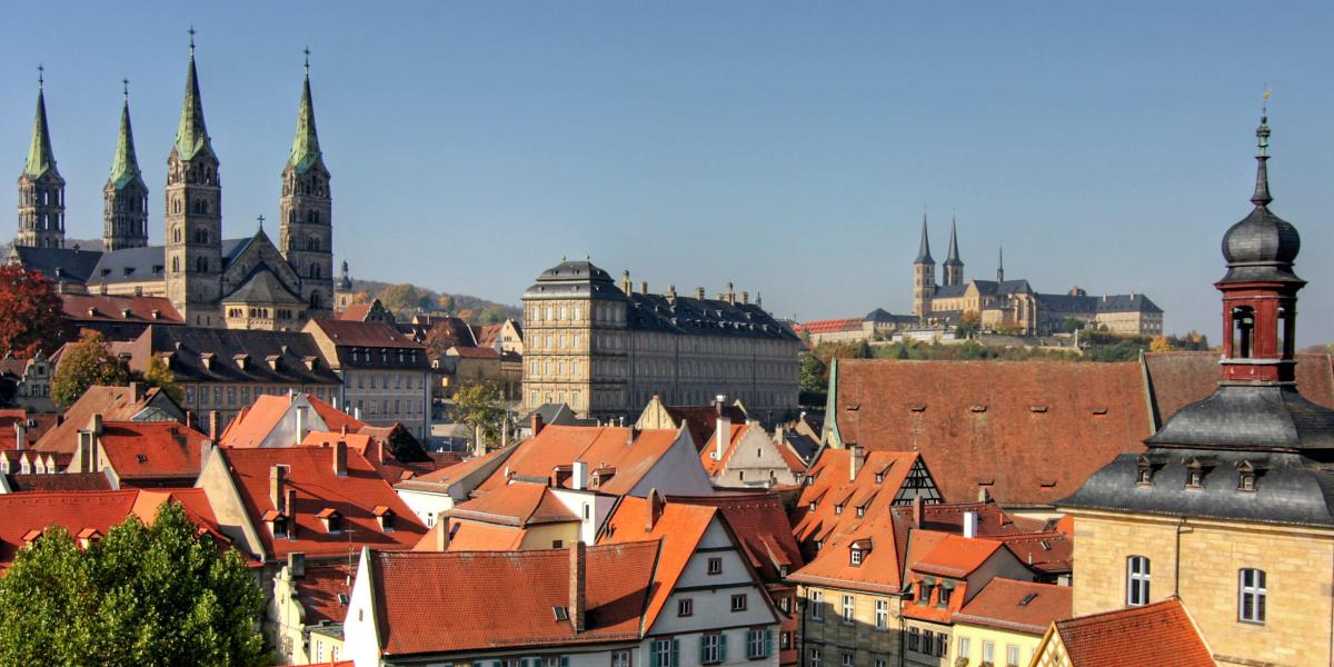 Altstadt von Bamberg mit rotem Ziegeldächern und Kirchtürmen im Hintergrund.