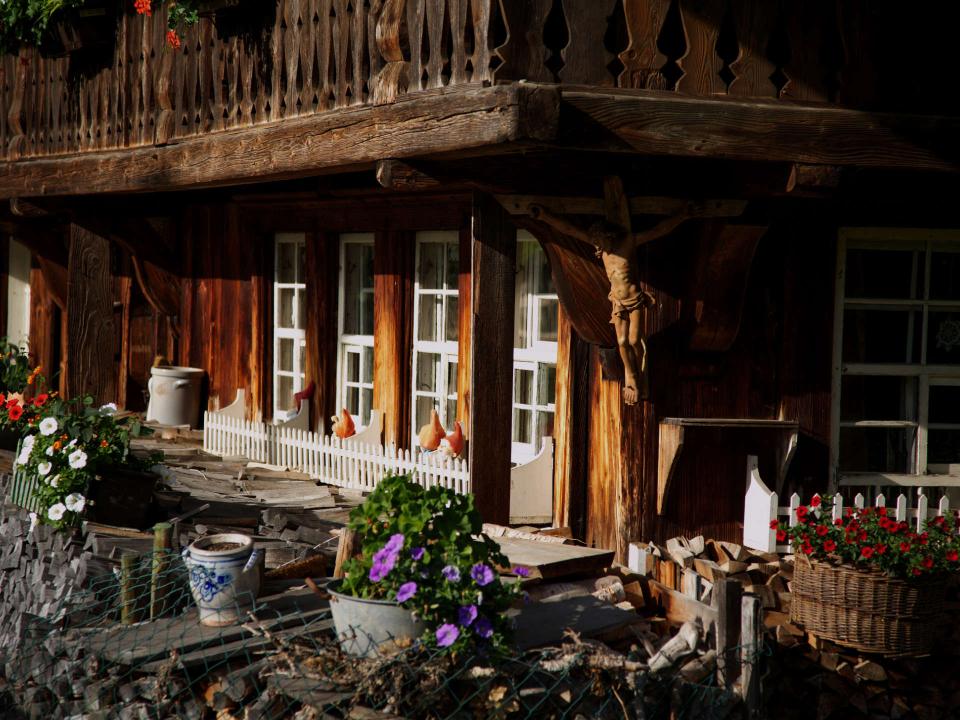 Traditionelle Schwazwaldhausfassade mit hölzernem Balkon und Blumenkästen sowie Brennholz vor der Tür____