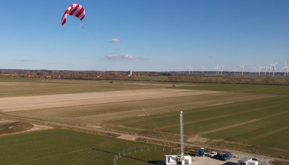 Die Windkraft-Anlage von "Skysails". Ein rot-weiß-gestreifter Windkraft-Drachen überragt zahlreiche Windräder.____
