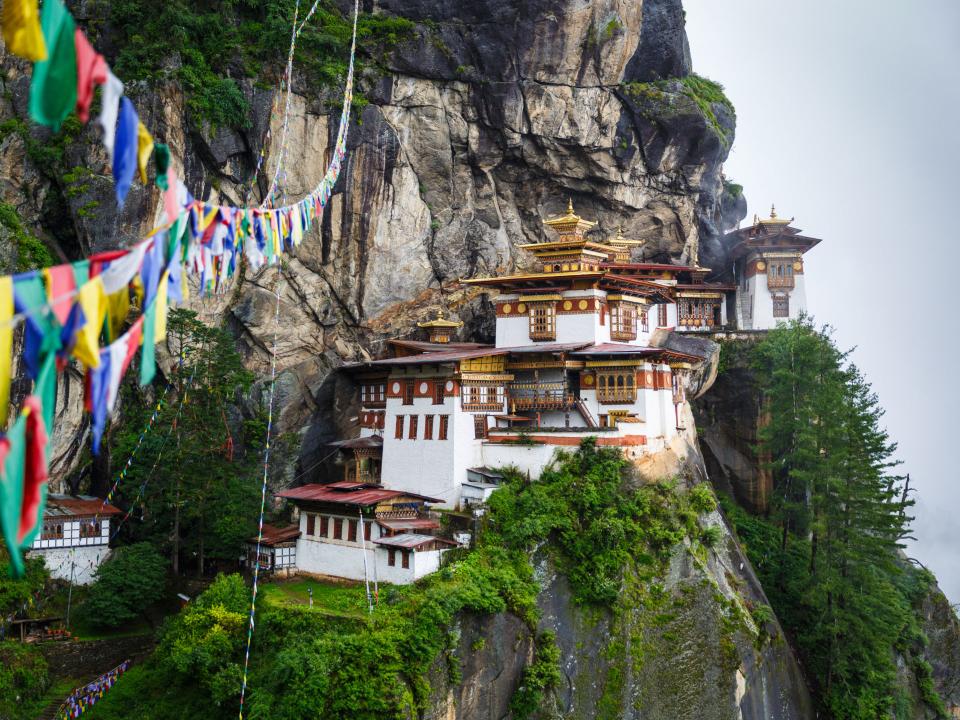Das Tigernest-Kloster an einer steilen Klippe mit bunten Gebetsfahnen in Bhutan.____