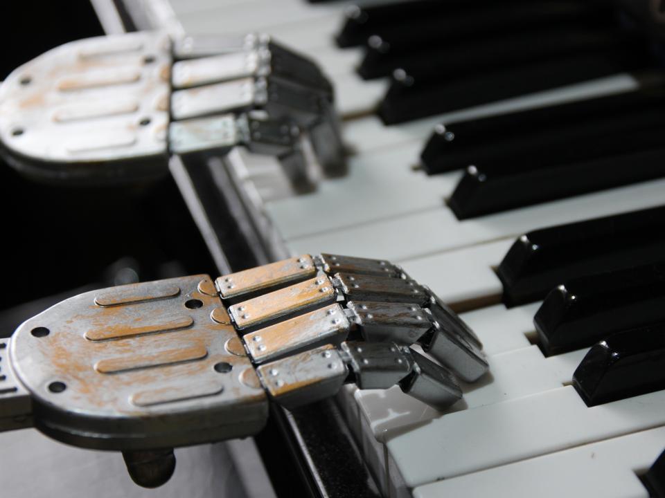 Roboterhände spielen auf einer Klaviertastatur, symbolisieren Künstliche Intelligenz in der Musik.____
