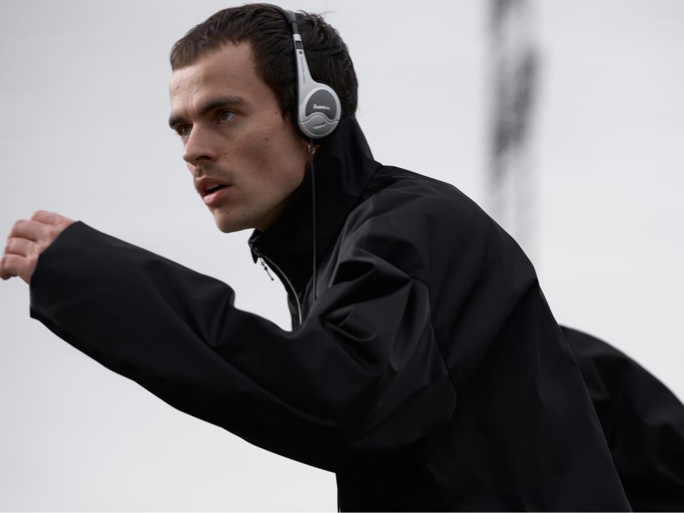 Mann mit Kopfhörern in schwarzer Jacke, fokussierter Blick, möglicherweise beim Sport oder Training.____