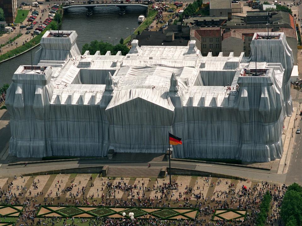 Luftbild des komplett silberverhüllten Berliner Reichstags mit deutscher Flagge und Besuchermengen im Vordergrund____