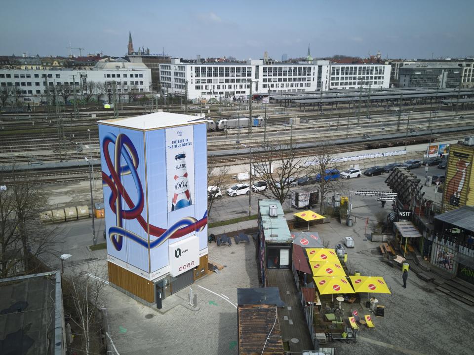 Vertikale Parkanlage nahe Gleisanlagen in München mit auffälligem Fassadendesign und Stadtpanorama.____