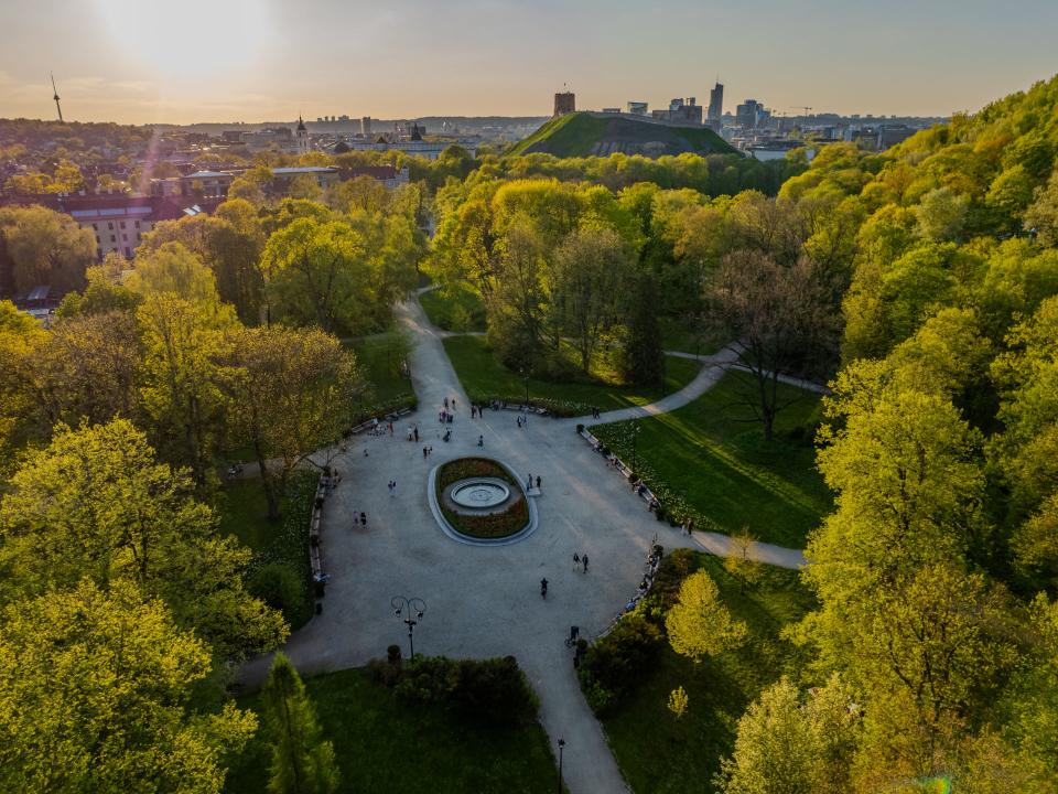 Luftaufnahme eines grünen Parks in Vilnius mit Brunnen, Spazierwegen und Besuchern.____