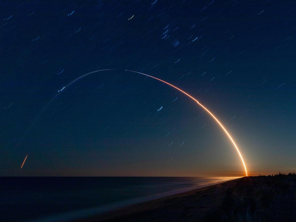 Leuchtende Flugbahn einer startenden Rakete über dem dunklen Himmel und Ozean.____