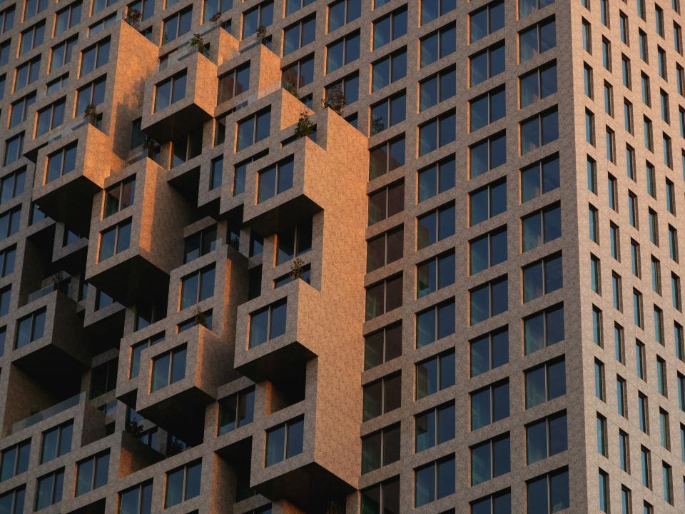 Detailaufnahme einer modernen Fassade mit würfelförmigen Balkonen und geometrischem Muster bei Abendlicht.____