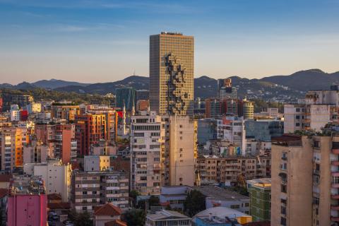 Skyline von Tirana mit modernem Hochhaus, das durch Pixelmuster-Fassade auffällt, urbane Architektur.