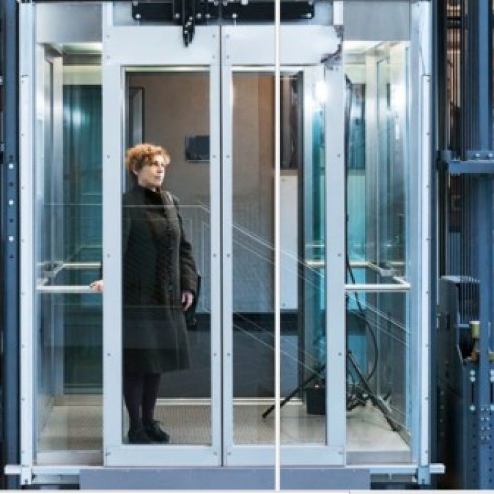 Dr. Babette Renneberg steht in einem gläsernen Aufzug____
