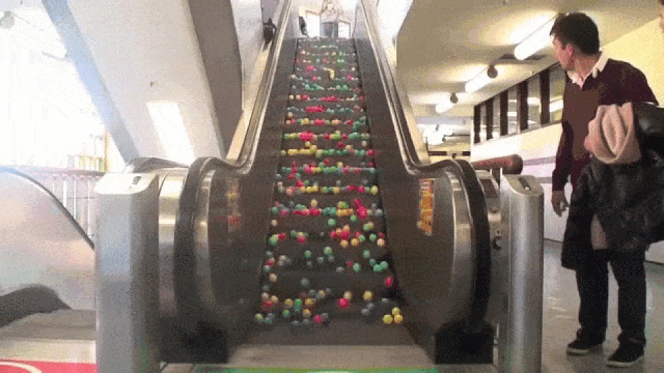 Animation von Bällen auf einer Rolltreppe. Daneben steht ein mann und wundert sich____
