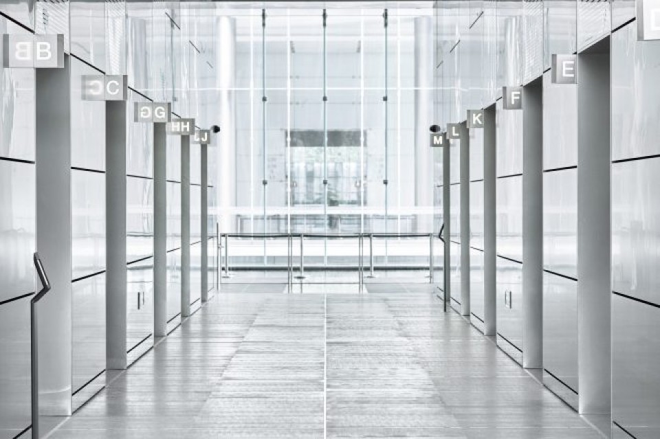 Ein Mittelgang in einem moderner Eingangsbereich in kühler Optik mit Aufzügen auf beiden Seiten____