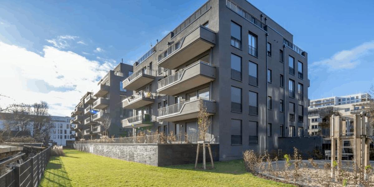 Schwarzes, moderne Mehrfamlienhaus mit einem gemähten Rasen im Vordergrund