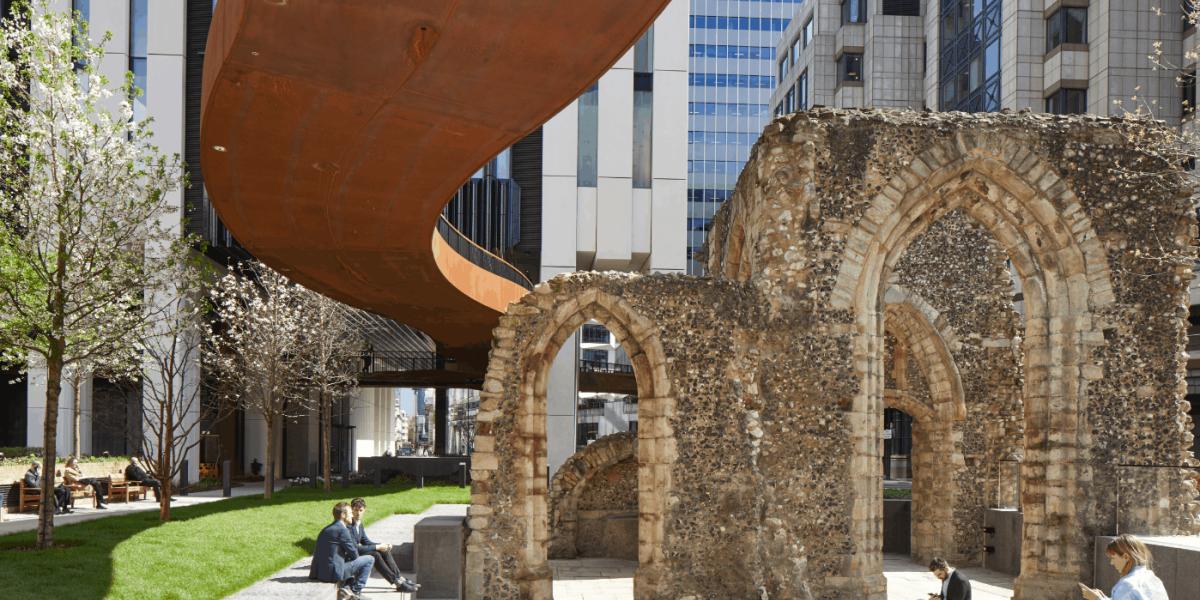 menschen sitzen in vor einer alten Ruine inmitten einer großen Stadt im Businessviertel