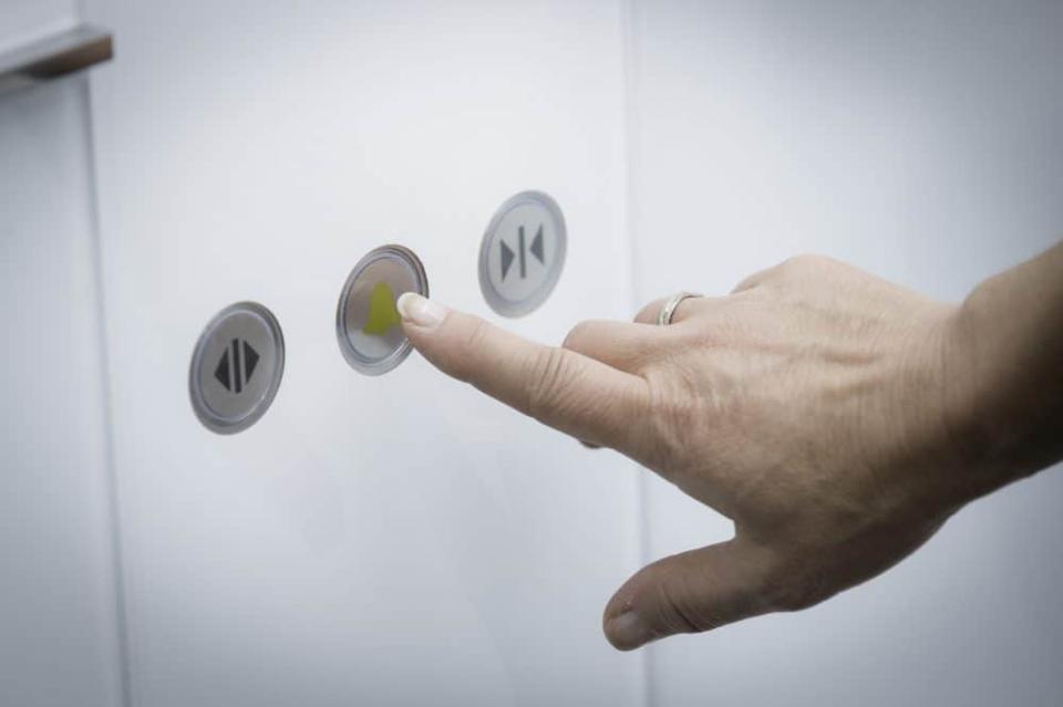 Eine Hand druckt auf die Notruftaster im Aufzug____