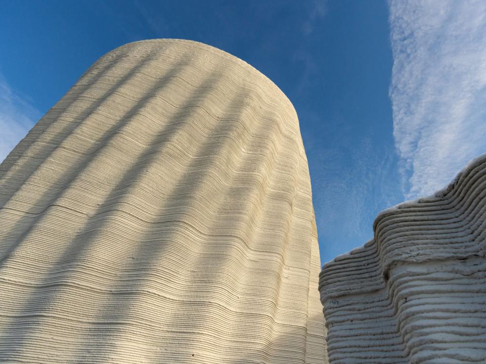 Außenansicht eines wellenförmigen 3D-gedruckten Gebäudes aus Beton – innovative Bauweise und Design.____