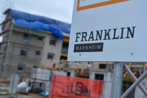 Projekt-Schild mit der Aufschrift Franklin Village im Vordergrund einer Baustelle
